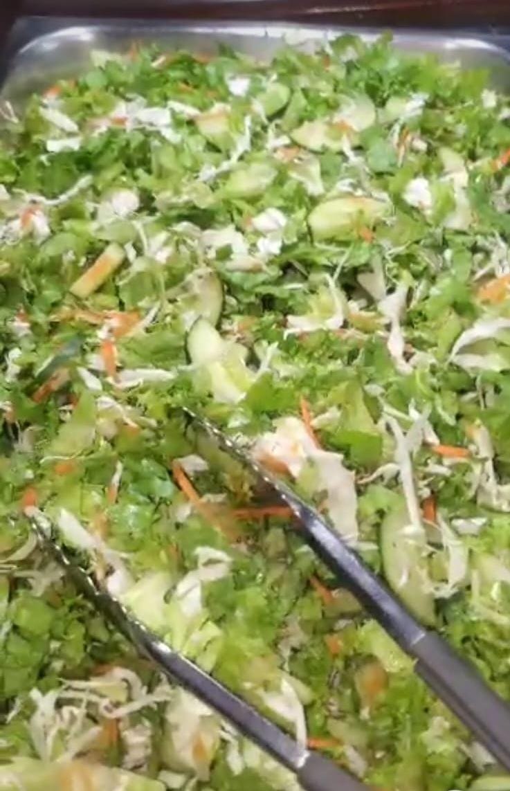 A tray of fresh garden salad with serving tongs
