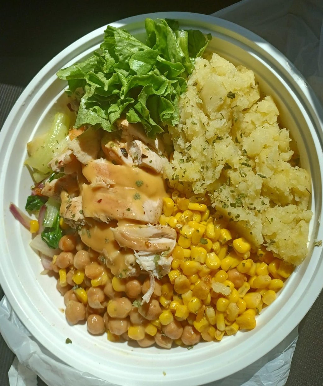 A lunch bowl with chicken, corn, chickpeas, potato and lettuce